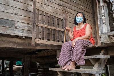 Senior woman wearing mask sitting outdoors