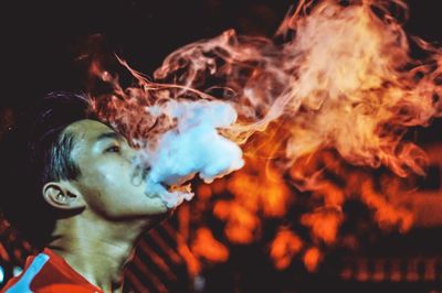 Close-up of man smoking at night