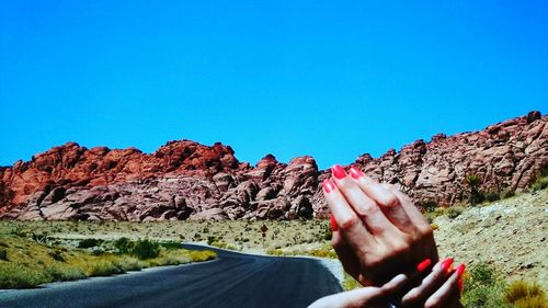 Woman standing on rocks against clear blue sky