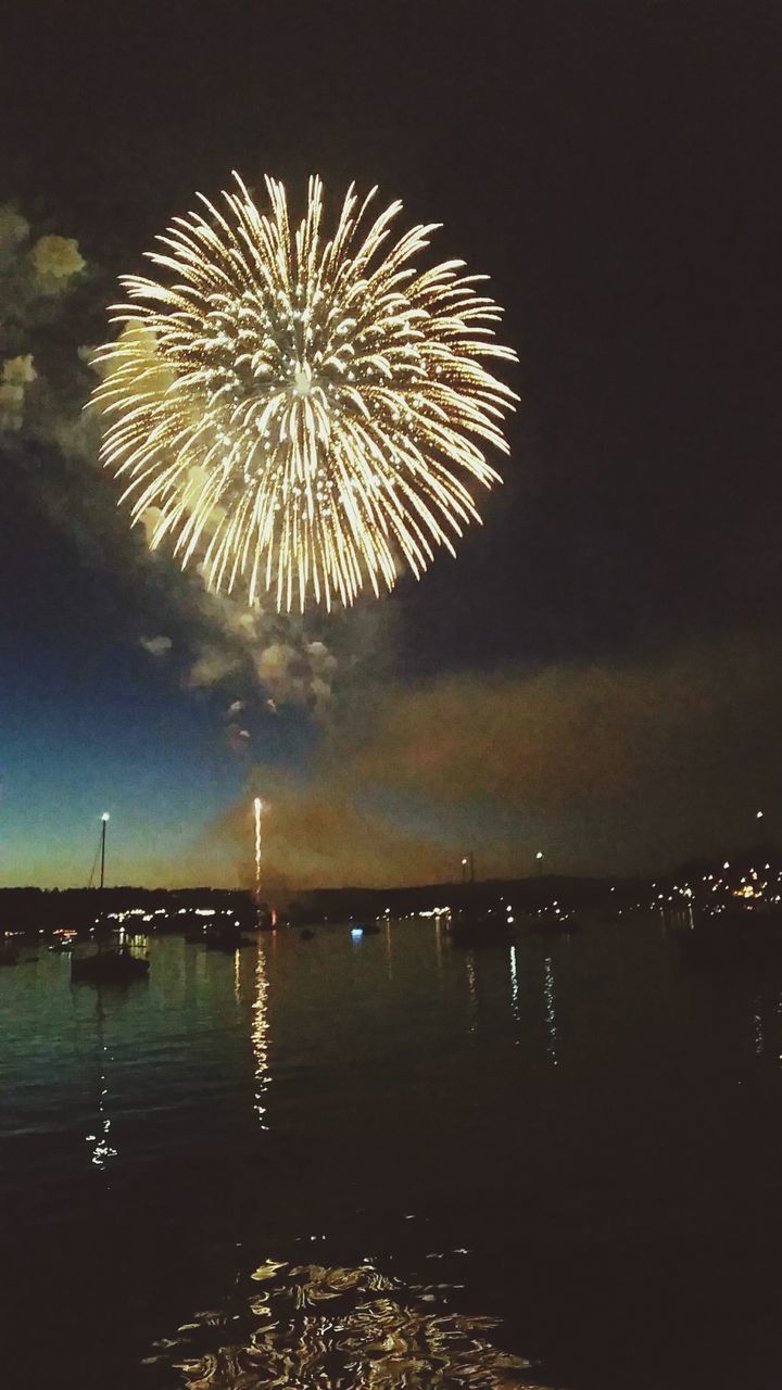 FIREWORKS DISPLAY OVER RIVER AT NIGHT