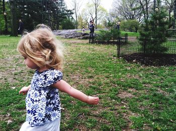 Girl standing on grass against trees