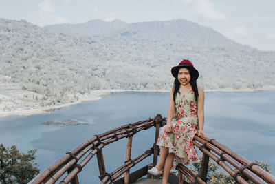 Portrait of young woman standing against sea