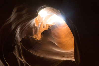 Low angle view of sunlight streaming through rock