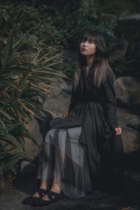 Portrait of young woman standing against plants