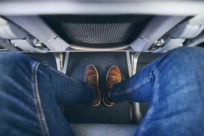 Low section of man wearing jeans sitting on airplane 