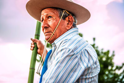 Side view of man wearing hat against sky