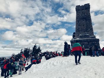 People on top of traditional building against cloudy sky
