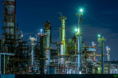 Low angle view of illuminated factory against sky at night