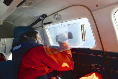 Side view of man shooting video in airplane