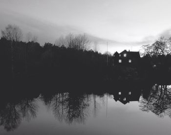 Reflection of silhouette trees in lake against sky