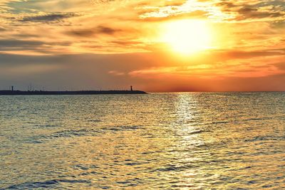 Scenic view of sea against dramatic sky during sunset