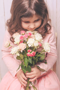 Smiling girl holding bouquet while sitting at home