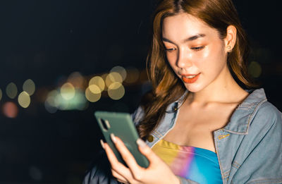 Close-up of young woman using mobile phone at night