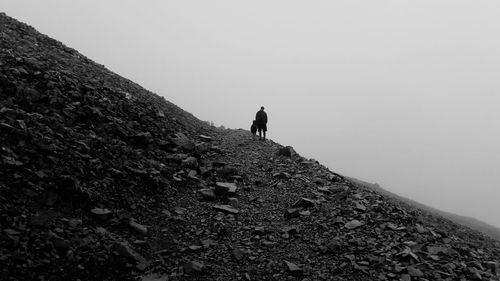 Father with child on mountain against clear sky