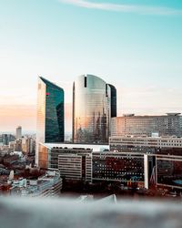 Modern cityscape against sky during sunset