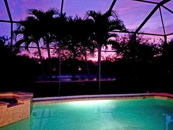 Swimming pool by trees against sky