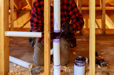 Low section of man standing on wood at home