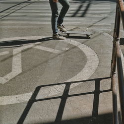 Low section of person with skateboard on sidewalk