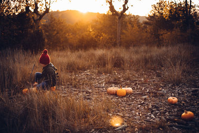 Full length of man sitting on field against sky during sunset