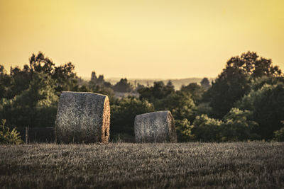 Hay bales on field against sky during sunset