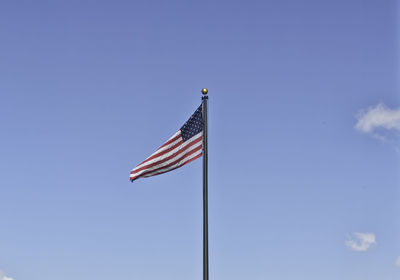 Low angle view of flag against blue sky