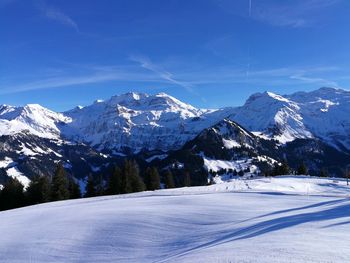 Scenic view of snowcapped mountains against blue sky