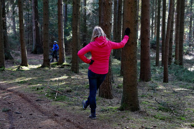 Rear view of woman standing against trees in forest