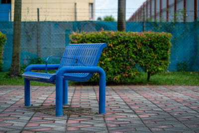 Empty bench on sidewalk in park