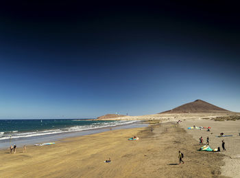 People on beach against blue sky