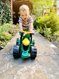 A toddler boy is playing with a toy tractor outdoors. a little cute boy of one and a half years 