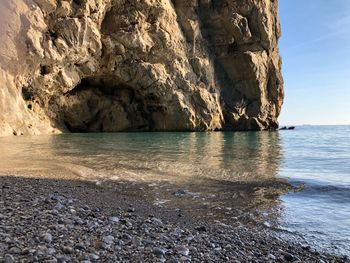 Rock formation on beach against sky