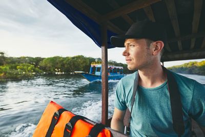 Young man looking away while sitting on boat