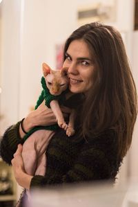 Portrait of smiling woman with cat sitting at home