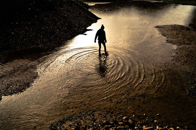 High angle view of silhouette person walking on puddle in field