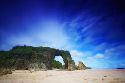 Scenic view of rocky beach against blue sky