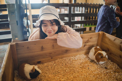 Smiling woman looking at hamster in wooden box 