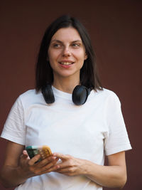 Pretty young woman with headphones listening to music though headset, smiling.