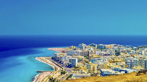 High angle view of sea by buildings against clear blue sky