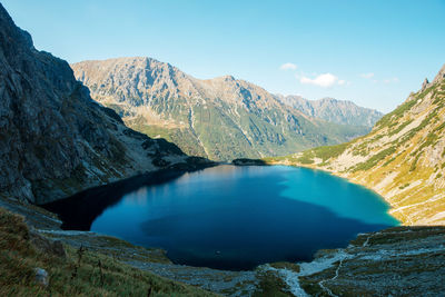 Scenic view of lake and mountains against blue sky