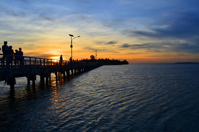 Silhouette pier over sea against sky during sunset