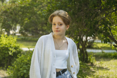 Young woman standing against trees