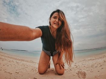 Portrait of beautiful woman on beach against sky