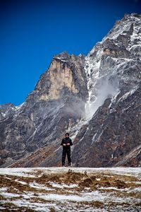 Man standing on snowcapped mountain against clear sky