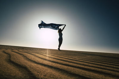 Low angle view of silhouette woman standing on street against sky