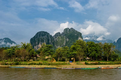 Kayak at riverbank in front of rocky mountain