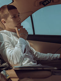 Side view of young woman sitting in car