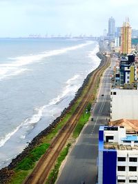 Aerial view of city by sea against sky