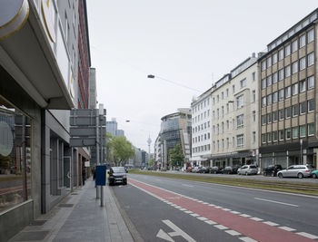 Cars on road amidst buildings against clear sky