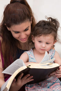 Close-up of mother reading book with daughter