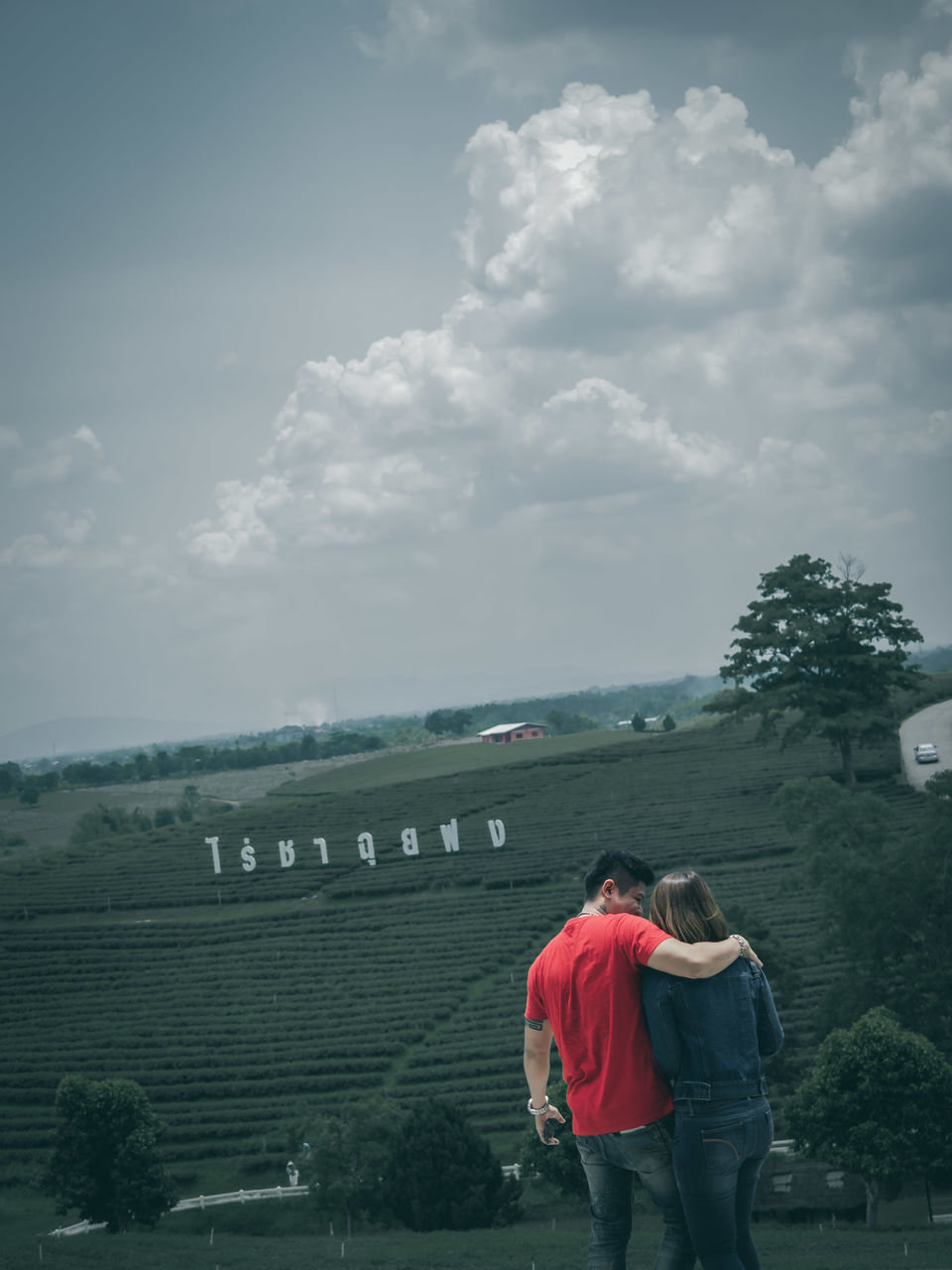 REAR VIEW OF MAN AND WOMAN STANDING AGAINST PLANTS